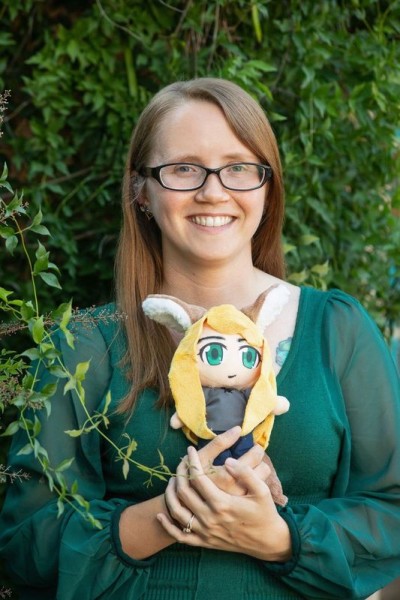 author picture of Valerie Storm holding a stuffed animal version of Kari, the wolf-demon.